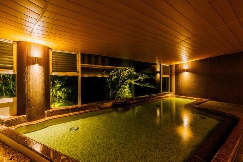 a swimming pool in a house with a window at KAMENOI HOTEL Izukogen in Ito