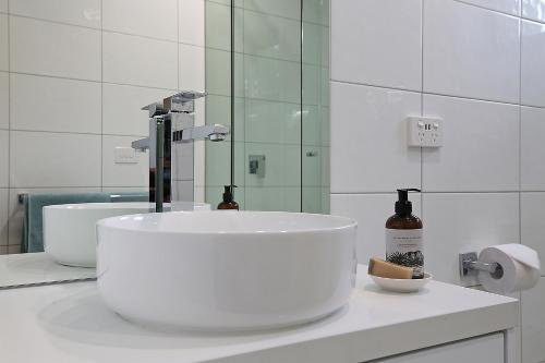 a white bathroom with a sink and a mirror at Timboon Tiny Homes in Timboon