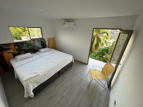 a bedroom with a large white bed and a chair at Apartamento Cómodo y encantador en cartagena in Cartagena de Indias