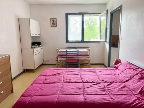 - une chambre avec un grand lit violet et une table dans l'établissement Studio confortable avec literie 140, cuisine équipée, parking à Cambo-les-Bains, sans internet - FR-1-495-120, à Cambo-les-Bains