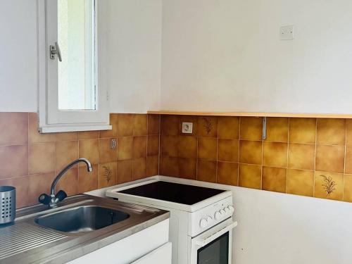 une cuisine avec un évier et une cuisinière dans l'établissement Studio confortable avec literie 140, cuisine équipée, parking à Cambo-les-Bains, sans internet - FR-1-495-120, à Cambo-les-Bains
