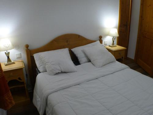 un lit avec des draps blancs et des oreillers dans une chambre dans l'établissement Charmant 2 pièces cabine avec parking et équipement modern à Samoëns - FR-1-629-121, à Samoëns