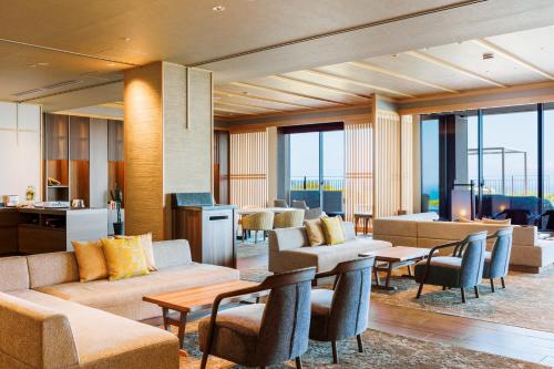 a hotel lobby with couches and tables and chairs at KAMENOI HOTEL Izukogen in Ito