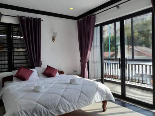 a bedroom with a white bed and a balcony at Paradise Cozy Guesthouse Sihanoukville in Sihanoukville