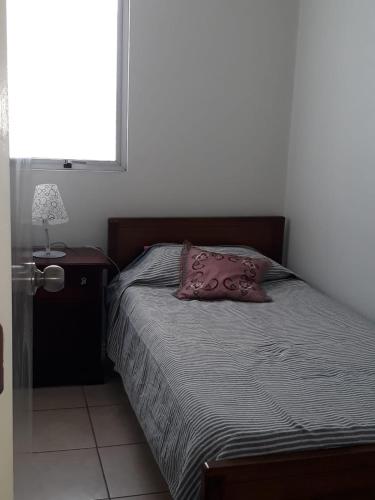 a bedroom with a bed with a pillow and a lamp at Departamento 5 minutos Playa cavancha in Iquique