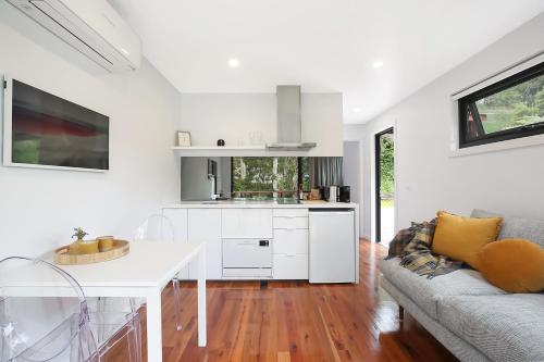 a kitchen and living room with white cabinets and a couch at Timboon Tiny Homes in Timboon