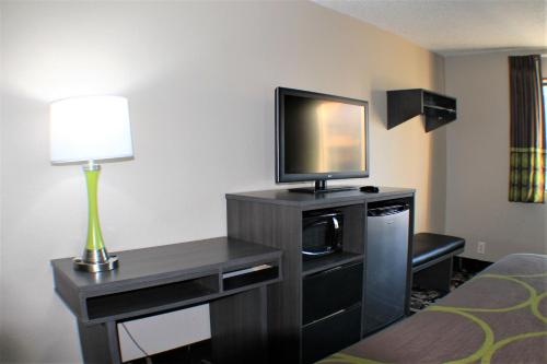 a hotel room with a television and a desk with a lamp at Super 8 by Wyndham Greensboro/Coliseum/Conv. in Greensboro