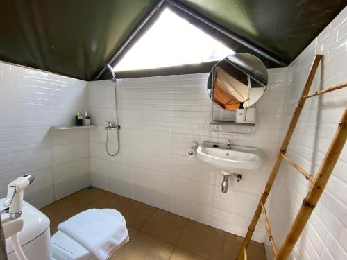 a bathroom with a toilet and a sink and a window at Alinson Sunset Hill in Bogor