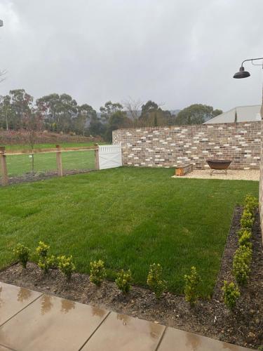 a yard with green grass and a brick wall at Bloomfield Manor in Bowral