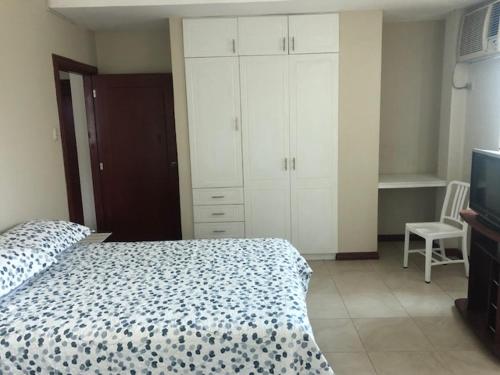 a bedroom with a bed and white cabinets and a tv at SUITE DORAL ¡¡CERCA DEL AEROPUERTO!! in Guayaquil