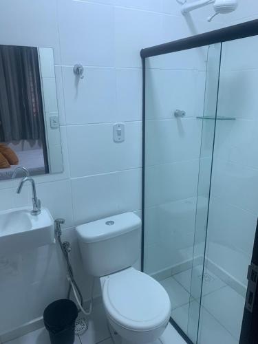 La salle de bains est pourvue de toilettes et d'une douche en verre. dans l'établissement Suítes Praia de Pajuçara, à Maceió