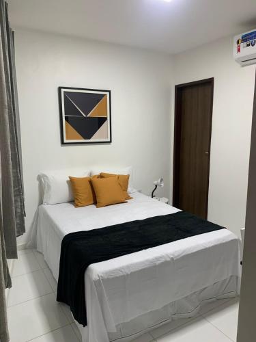 Suítes Praia de Pajuçara في ماسيو: غرفة نوم بسرير ابيض كبير مع مخدات صفراء