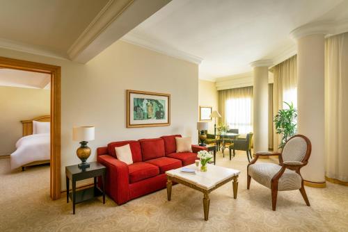 a living room with a red couch in a hotel room at Mövenpick Hotel Doha in Doha