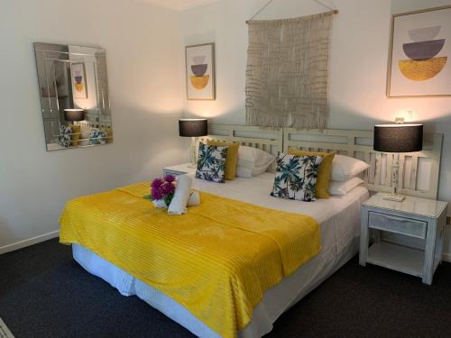 a bedroom with a large bed with a yellow blanket at Ramada Resort - Stylish Deluxe Apartment in Port Douglas
