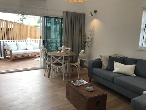 a living room with a couch and a table at Seabirds Cottage in Coffs Harbour