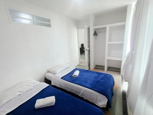 two beds in a small room with blue sheets at Apartamento Agradable sector Céntrico de la Ciudad Casa Loma in Armenia