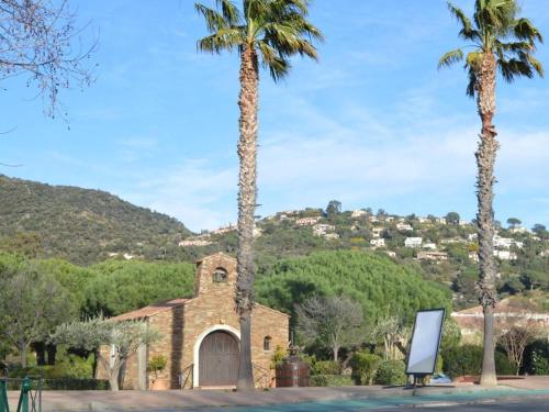 une église avec des palmiers en face d'une montagne dans l'établissement Appartement cosy avec terrasse et parking, à 2 pas de la plage de Saint-Clair - Ménage inclus - FR-1-251-12, au Lavandou
