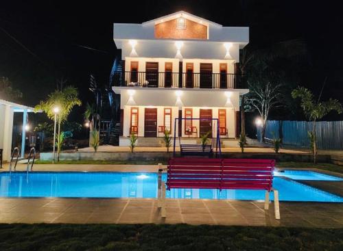 een huis met een zwembad en een bank ervoor bij The Lavender Resort Waynad in Vaduvanchal