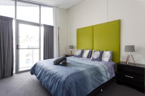 a bedroom with a large bed with a green headboard at Waverley apartment A-two bedrooms wifi available in Perth