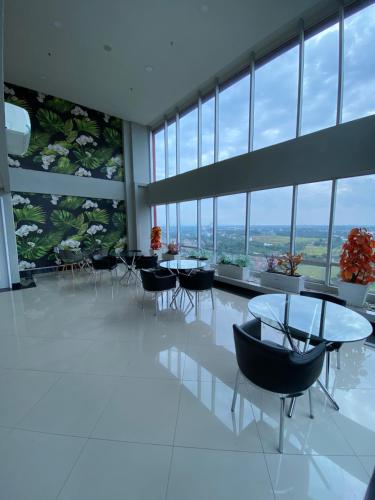 a large room with tables and chairs and windows at Parkland Avenue Serpong BSD - Locca cafe in Babakan