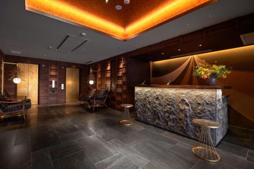 a lobby with a bar with stools and chairs at Minn Kanazawa in Kanazawa