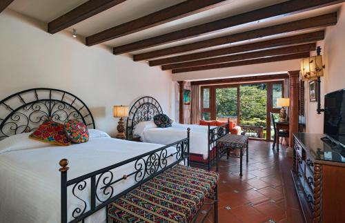 a bedroom with two beds and a living room at Hotel Atitlan in Panajachel
