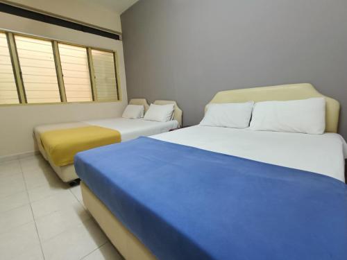 a room with two beds and two windows at Kota Lodge in Melaka