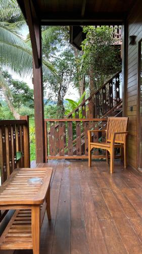 a wooden porch with two benches and a table at Big Tree Cottages in Beadonābād