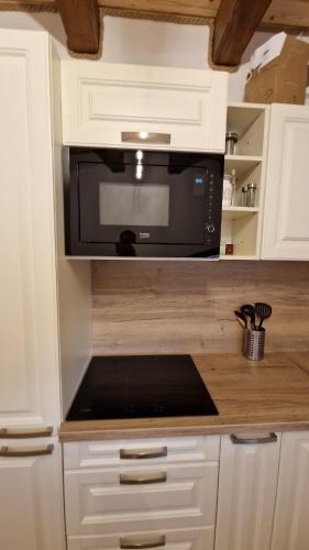 a kitchen with a black microwave in a white kitchen at Mytho 1 in Mýto pod Ďumbierom