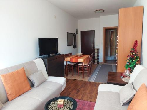 a living room with a white couch and a christmas tree at Apartman Pahuljica Vlašić in Vlasic