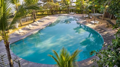 einen Blick über einen Pool mit Liegestühlen und einer Palme in der Unterkunft LUX* Grand Gaube Resort & Villas in Grand-Gaube