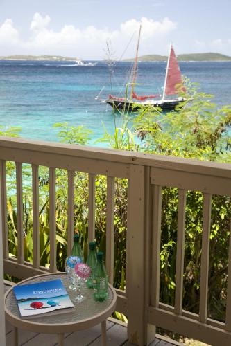 a table on a balcony with a boat in the water at Gallows Point Resort in Saint John
