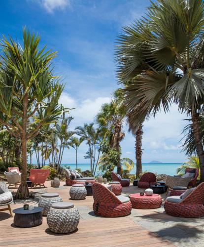 a patio with chairs and palm trees and the ocean at LUX* Grand Gaube Resort & Villas in Grand Gaube