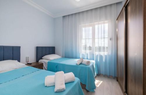 a blue room with two beds and a window at Super in Belek