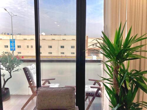 Cette chambre dispose d'une fenêtre avec une chaise et des plantes. dans l'établissement Inbar Residence إنبار ريزدينس شقة عائلية متكاملة, à Riyad