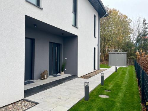 a white house with a courtyard with green grass at NEU! Feriendomizil TraumZeit 1 mit Sauna & Garten in Göhren-Lebbin