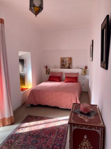 a bedroom with a bed with red pillows and a table at Riad SASHA in Marrakesh
