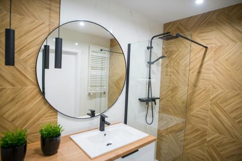 a bathroom with a sink and a mirror at Nowoczesny apartament Ludova in Biskupiec