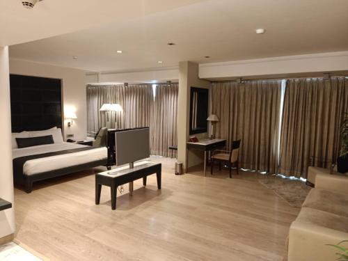 a bedroom with a bed and a desk and a television at Mirage Hotel, Mumbai International Airport in Mumbai