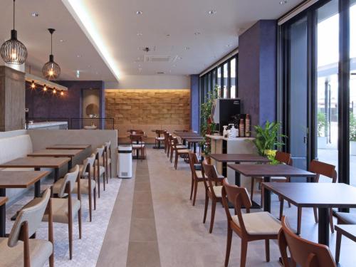 um restaurante com mesas, cadeiras e janelas em Hotel Granbinario Tsuruga em Tsuruga