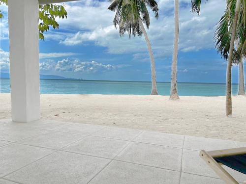 an empty beach with palm trees and the ocean at Lime N Soda Beachfront Resort in Thongsala
