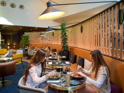 Dos mujeres sentadas en una mesa en un restaurante en Mercure Antwerp City South en Amberes