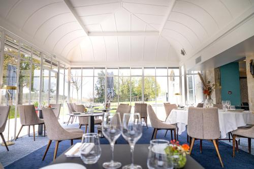 a restaurant with tables and chairs and windows at Hôtel Mercure Rochefort La Corderie Royale in Rochefort