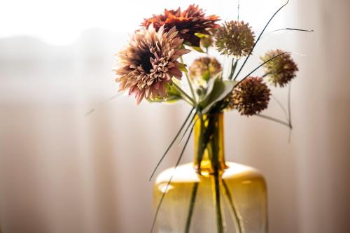 a yellow vase filled with flowers sitting on a table at Best Western Plus Hotel Cargo in Dunkerque