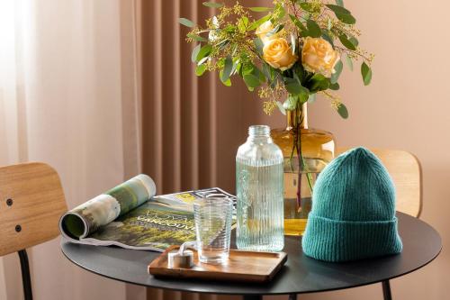 a table with a vase of flowers and a hat on it at Best Western Plus Hotel Cargo in Dunkerque