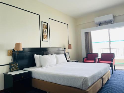 ein Hotelzimmer mit einem Bett und zwei roten Stühlen in der Unterkunft Seaview Suite at Rainbow Paradise in Tanjung Bungah