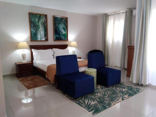 a hotel room with a bed and two blue chairs at Inhambane Hotel Escola in Inhambane