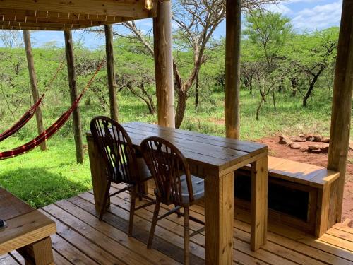 a wooden table and chairs on a porch with a hammock at Mudhouse Zululand in Hluhluwe