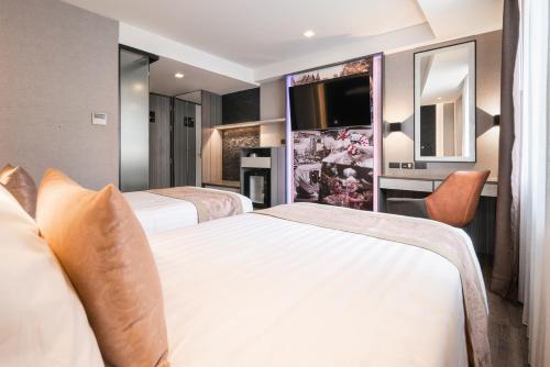 a hotel room with two beds and a flat screen tv at Aspira Gems Center Silom in Bangkok