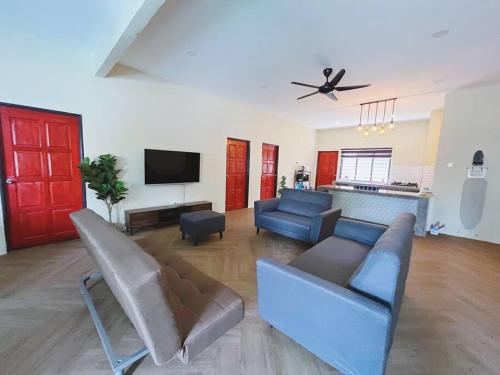 Una sala de estar con un sofá y un televisor. en Villa D'Razna - Luxury 5-bedroom Villa with private pool, en Kuala Terengganu